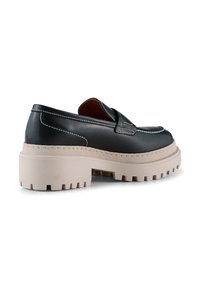 Crna kožna slip-on cipela s debelim bež gumiranim potplatom, koja ima bijele šavove i glatku završnu obradu. Zaobljen vrh i plastični dizajn.