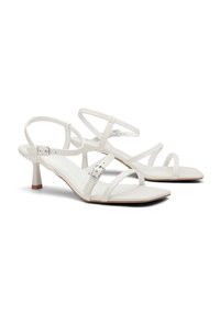 Sandales à talons blancs en cuir lisse, avec des fines lanières, un design à bout carré, une boucle réglable à la cheville et un talon effilé.
