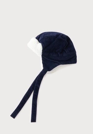 Marineblaue Cord-Wintermütze mit weißem Fleecefutter und langen Bändern zum Binden unter dem Kinn auf hellem Hintergrund.