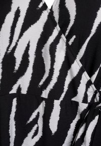 Črnobela tkanina z vzorcem vsebuje drzne zebra proge, podobne čopičnim potezam. Tekstureta površina s stilom zavijanja in detajlom v vezi.