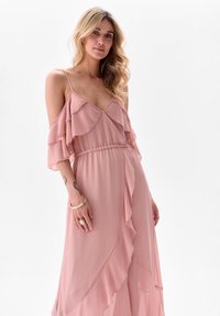 Roze chiffon jurk met gerimpelde mouwen, een cinched taille en een vloeiende uitstraling. De stof heeft een zachte textuur en valt elegant.