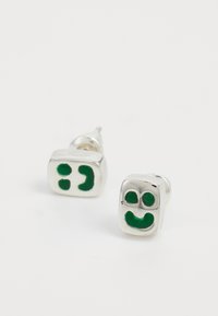 Sudraba auskari ar taisnstūra formu, rotāti ar zaļiem smaidošiem un mirkšķinošiem sejas dizainiem, ar pulētu apdari un gludu tekstūru.