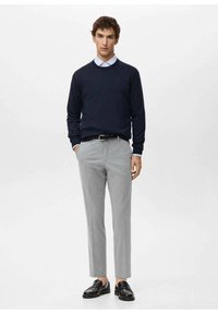 Navy knitted sweater, light blue collared shirt, gray tailored trousers, and black loafers. Simple design with a fitted silhouette.
