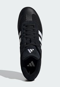 Czarne buty sportowe z siateczkową cholewką, kontrastującymi białymi paskami i czarnymi sznurówkami. Wyróżniające się fakturowane akcenty oraz logo na języku.