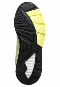 Melna un dzeltena gumijas zole ar teksturētām berzes rakstiem, ar izteiktu Adidas logo un dažādām izvirzījumiem saķerei.