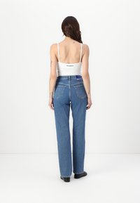 Jeans de tiro alto y pierna recta en un tono azul con un acabado de denim texturizado. Presenta bolsillos traseros y una etiqueta en contraste en la cinturilla.