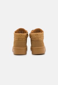 Tans kleurige mid-top sneakers gemaakt van gladde en gestructureerde materialen, voorzien van een gewatteerde kraag, ritssluiting en rubberen zool.