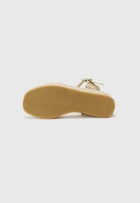Sandalo con tomaia beige chiaro e punta quadrata, caratterizzato da cinturini sottili e una suola in gomma leggera marrone chiaro texture.
