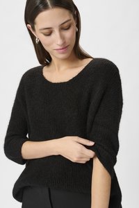 Melna adīta džemperis ar plašu koledžveida kakla izgriezumu un 3/4 garuma piedurknēm. Audums izskatās mīksts ar teksturētu apdari un brīvu piegriezumu.