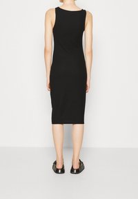 Czarna, prążkowana sukienka do kolan o bezrękawowym kroju, z okrągłym dekoltem. Połączona z czarnymi, płaskimi butami wsuwanymi.