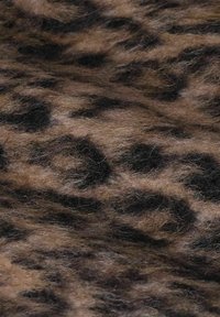 Tissu en motif animalier avec une surface douce et texturée, présentant une base brun clair et des taches de léopard allant du brun foncé au noir.