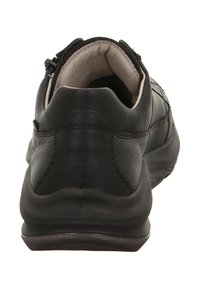 Schwarzer Lederschuh mit gepolstertem Knöchelkragen, genähten Details und flexibler Gummisohle. Die Rückseite zeigt eine glatte, abgerundete Form.