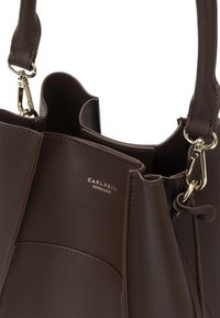 Sac à main en cuir brun foncé avec fermoirs dorés et bandoulière amovible, arborant le logo CARLHEIM Copenhagen sur le panneau avant.