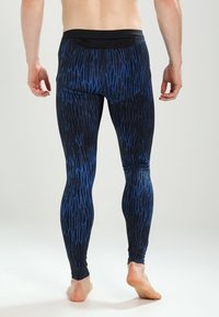 Svart och blå mönstrade leggins med en elegant, stretchig design. Har en hög midja och texturerad detaljering genom hela.