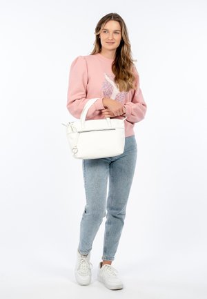 Sac à main en cuir blanc avec fermeture éclair, au design structuré et deux poignées courtes. Le mannequin porte un sweat-shirt rose et un jean bleu clair.