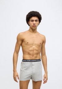 Γκρι ανδρικά μποξέρ με μαύρη μέση που φέρει το λογότυπο "Karl Lagerfeld". Απαλό ύφασμα, χαλαρή εφαρμογή και λεπτομέρεια με κουμπί μπροστά.