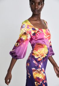 Blumenkleid aus Satin mit quadratischem Ausschnitt, Puffärmeln und taillierter Silhouette. Es besticht durch lebendige Farben in Pink, Lila und Gelb sowie aufwendige Blumenmuster.