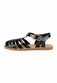 Sandalo in gel nera con design incrociato, suola piatta e una fibbia decorativa con strass sulla cinghia alla caviglia.