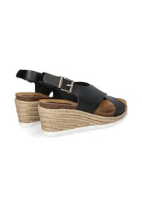Schwarze Leder-Wedgesandalen mit breitem Vorderriemen, verstellbarem Schnallenverschluss und geflochtenen Jute-Details auf einem hohen Keilabsatz.