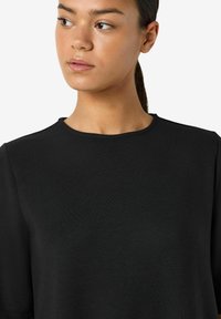 Czarna koszulka z krótkim rękawem, z klasycznym okrągłym dekoltem i miękką, gładką fakturą. Prosty, minimalistyczny design bez ozdób.