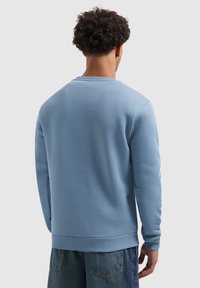 Lichtblauwe sweatshirt met geribbelde kraag en manchetten, met een gladde textuur en een relaxte fit. Achteraanzicht, gedragen met denim shorts.