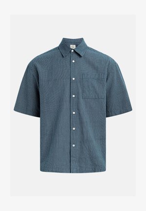 Camisa de manga corta con botones, patrón a cuadros pequeños en azul y blanco, y bolsillo en el pecho sobre un fondo liso.