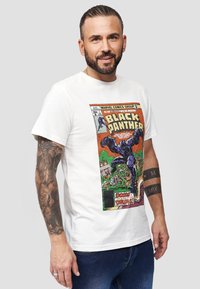 Vit bomull t-shirt med tryck av Black Panther i serietidningsstil, med livliga färger, detaljrika karaktärer och en klassisk vintage-design.