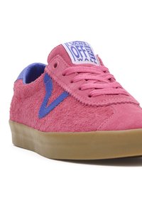 Pink suede sneaker with a textured finish, blue accents, and a beige rubber sole. Features a lace-up design and logo on the tongue.
