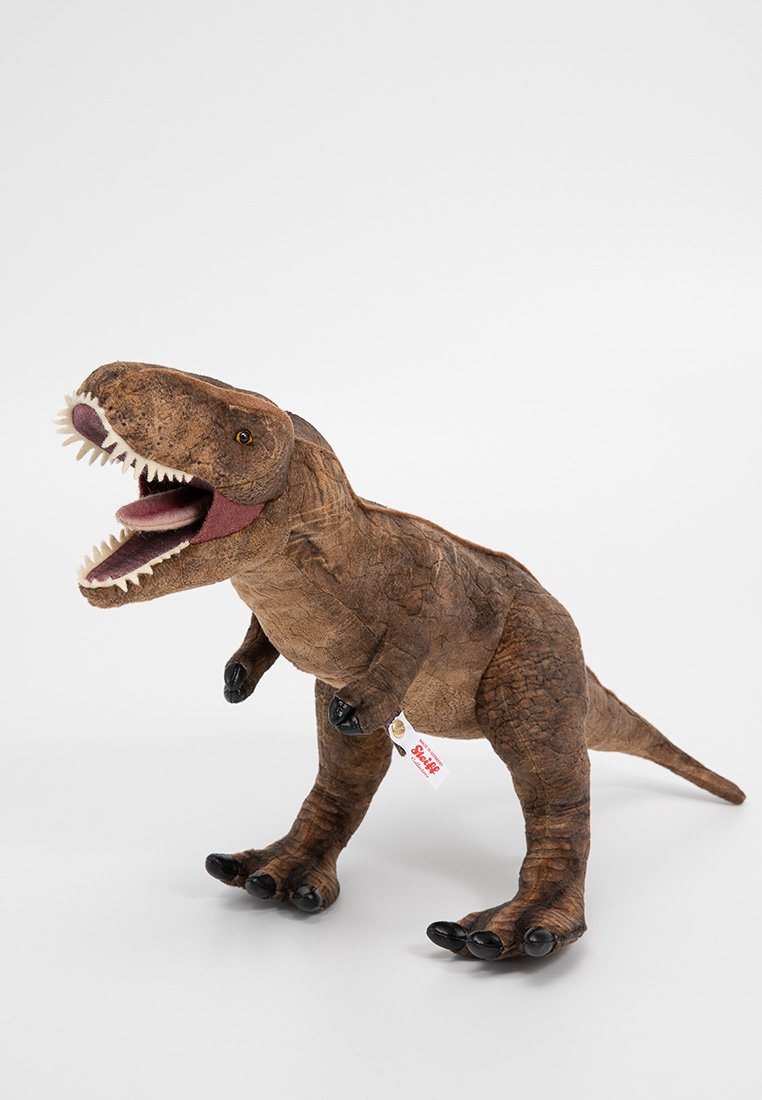 Plüsch Tyrannosaurus rex Spielzeug mit einem braunen strukturierten Körper, weißen Zähnen und schwarzen Klauen. Detailliert mit gelben Augen und einem rosa Innenteil des Mundes.