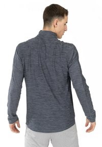 Langsleeve, donkergrey sportshirt met een gestructureerd patroon en staande kraag, ontworpen voor comfort tijdens fysieke activiteit.