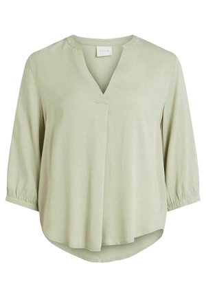 Blouse vert clair avec un col en V, des manches trois-quarts à poignets froncés et un ourlet courbé pour un ajustement décontracté. Texture lisse et douce.