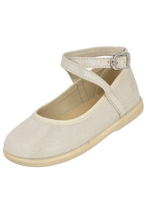 Zapato plano beige con puntera redondeada y correa en el tobillo con hebilla plateada, diseñado para uso casual o vestir.