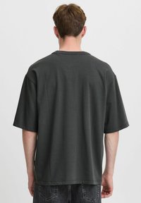 Tamno siva oversized majica od pamuka, s kratkim rukavima i okruglim izrezom, s glatkom teksturom i minimalističkim dizajnom.