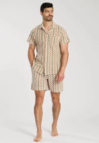 Conjunto de camisa de manga corta con cuello y pantalones cortos en un patrón de zigzag con tonos beige, óxido y verde, hecho de una tela ligera.