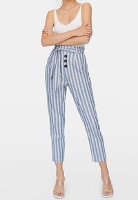 Pantalon taille haute rayé bleu et blanc avec ceinture à nouer, comportant trois boutons décoratifs et une longueur raccourcie.