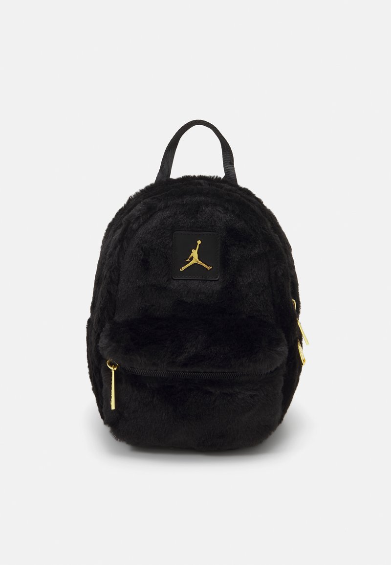 Svart faux fur ryggsekk med avrundet design, med et gulllogo-patch og to glidelåslommer med gullglidelåser.