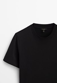 T-shirt nera a manica corta realizzata in un tessuto morbido, con scollatura rotonda e bordi puliti, mostrata su uno sfondo bianco.