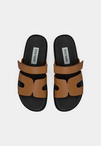 Brune slidesandaler med udskæringsdesign, syntetisk overdel, justerbar rem, sort polstret sål og struktureret sål for godt greb.