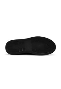 Semelle de chaussure noire en matériau caoutchouc, surface texturée, motif en chevrons et design plat. Comprend une sangle centrale pour une meilleure adhérence.