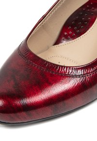 Rote Lackleder-Ballerinas mit runder Spitze und glatter Oberfläche; ausgestattet mit Kontrastnähten und einer leicht gepolsterten Innensohle.