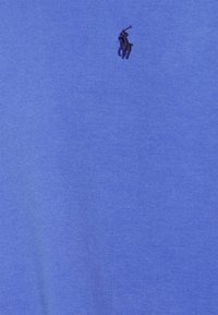 Modré bavlněné tričko s kulatým výstřihem a krátkými rukávy, s malým černým logem polo na levé straně hrudi. Měkká textura, ležérní design.