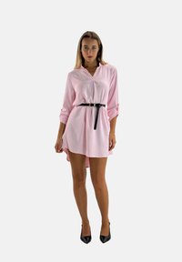 Roze jurk met kraag, lange mouwen opgerold, cinched in de taille met een zwarte riem en een high-low zoom.