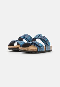 Sandalias de patrón azul con doble tira negra, plantilla de corcho y suela de goma texturizada; presenta hebillas ajustables para un mejor ajuste.