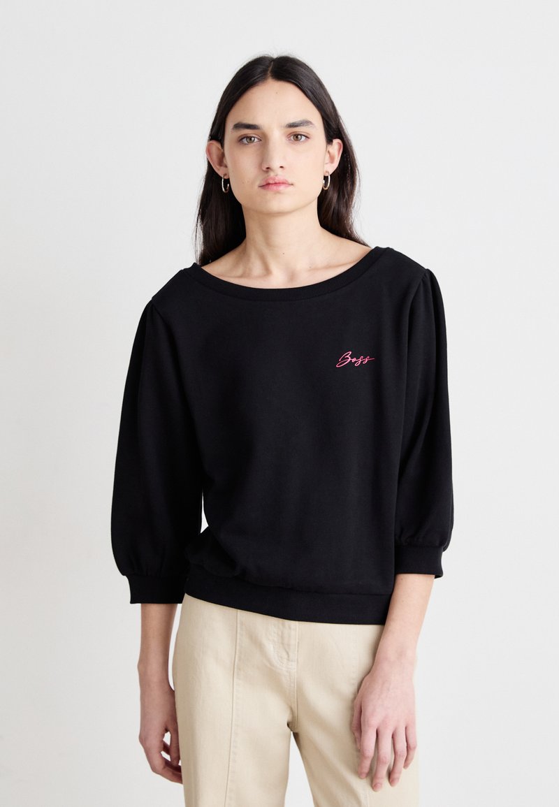 Felpa nera con scollatura ampia e maniche a sbuffo. Presenta un ricamo rosa con la scritta "Boss" sul petto. Tessuto in cotone morbido e strutturato.