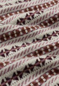 Audums krēma, rozā un brūnā toņos ar ģeometrisku rakstu. Mīksts, teksturēts vilnas materiāls izceļ sarežģītus dizainus un krāsas.