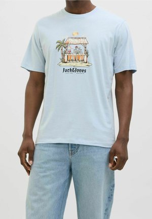 Jasnoniebieska koszulka z tropikalnym motywem baru, na którym widoczne są dwie szkielety, palma, butelki oraz napis „Jack & Jones” na przodzie.