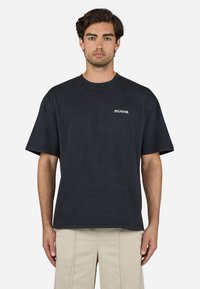 Donker marineblauwe katoenen t-shirt met korte mouwen, ronde halslijn en wit "Pegador" logo op de linkerborst. Normale pasvorm, gladde textuur.