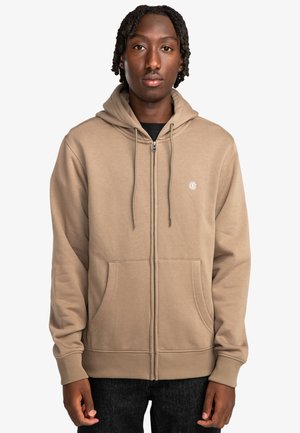 Chaqueta con cremallera color beige hecha de material suave, con capucha ajustable, dos bolsillos frontales y un logo bordado en el pecho.