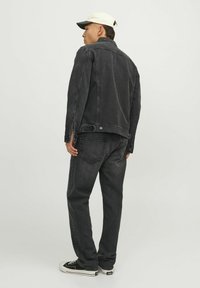 Svart jeansjacka och jeans med avslappnad passform. Jackan har smala slag, knäppning med knappar och sidofickor. Outfitten är kombinerad med svarta sneakers.