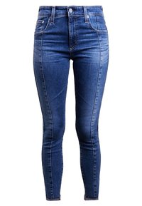 Džíny v vysokém pasu v středně modré denimové barvě, s předními kapsami, zipem a jemným vyblednutím na nohavicích.